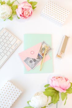A stylish flat lay with a keyboard, flowers, and stationery on a white background.