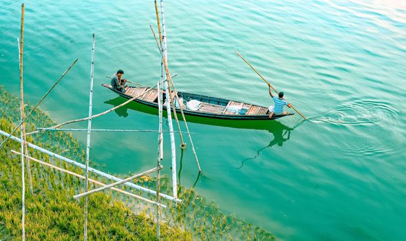 Ethnic men floating on canoe along pure blue lake