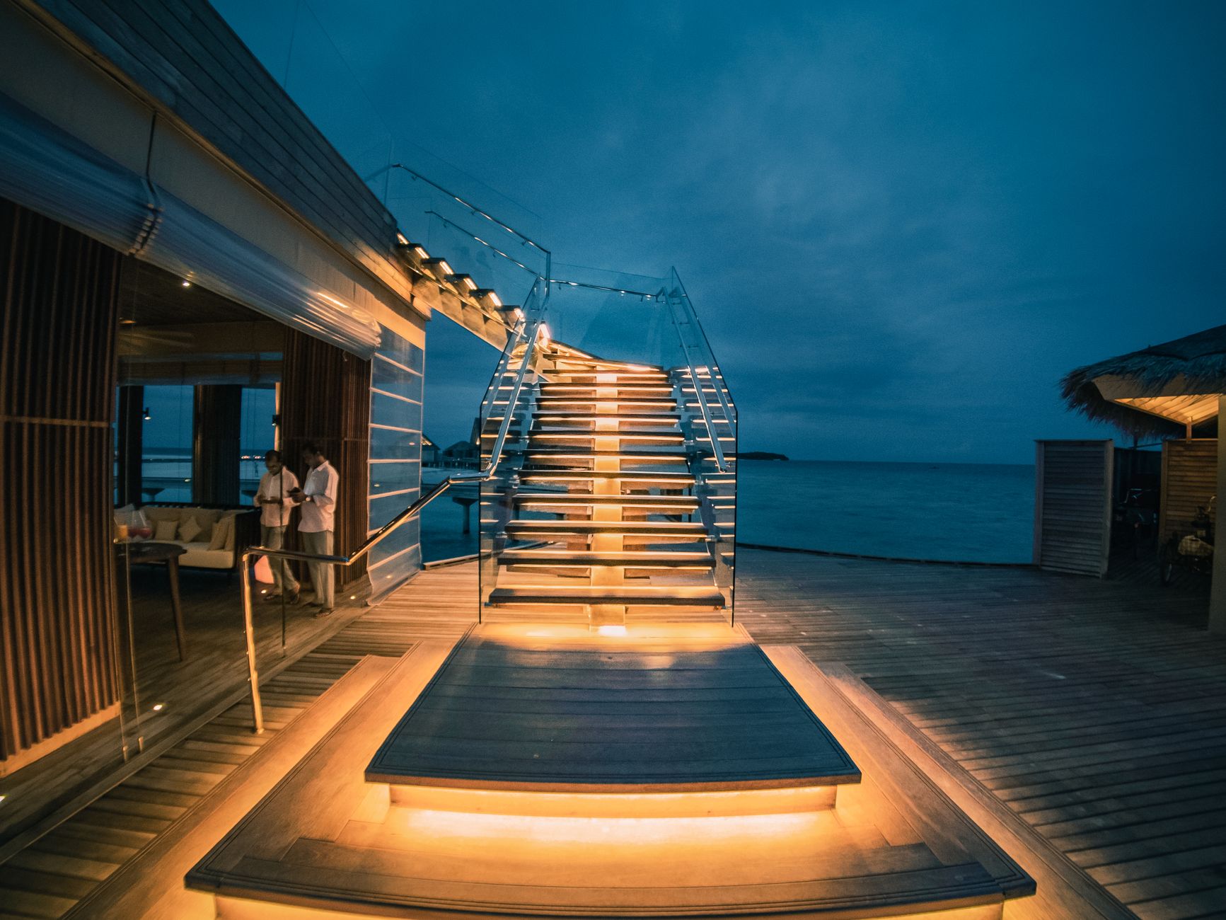 Contemporary tropical resort villa located on seafront with big stylish outdoor staircase and veranda in evening
