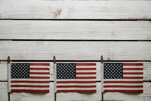 Free Top view hand waving national flags of United States of America placed on wooden plank desk Stock Photo