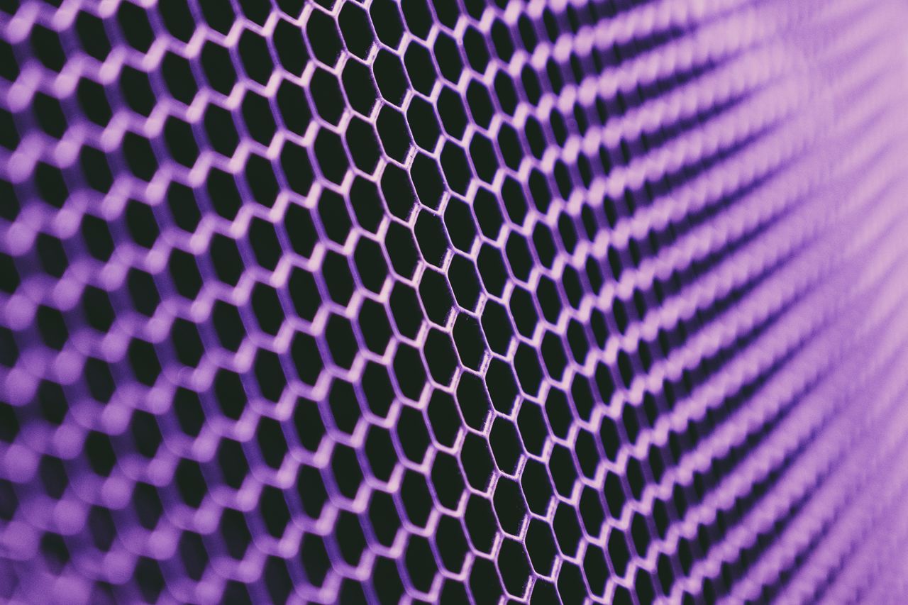 thin metallic net cell of hex shape and bright violet color against bl