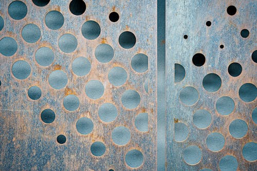 Free Thin rusted corrosion metal panels with carved circles of different size against gray wall Stock Photo