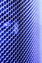 Abstract background of thin metal net cells of hex shape in bright blue light