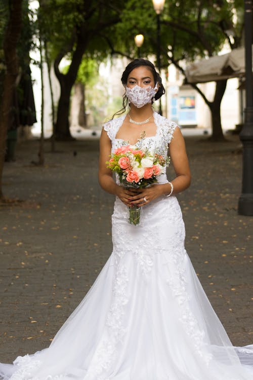 Woman in White Wedding Dress Holding Bouquet of Flowers