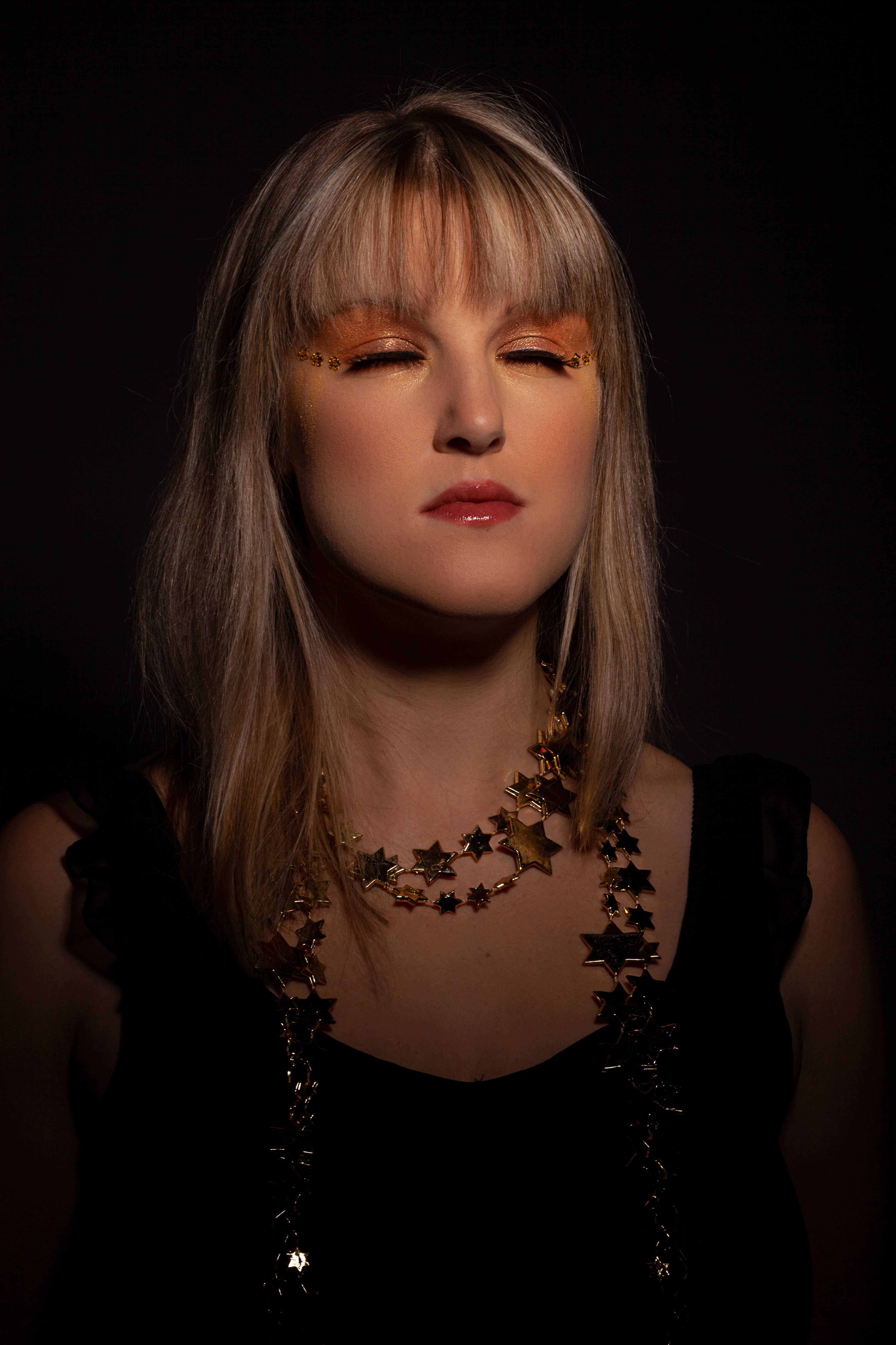 Studio portrait of a woman with closed eyes and glamorous makeup, highlighting elegance and sophistication.