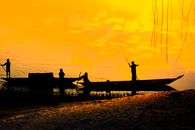 Anonymous fishermen in boat on lake shore at sunset