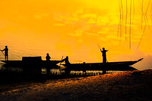 Anonymous fishermen in boat on lake shore at sunset