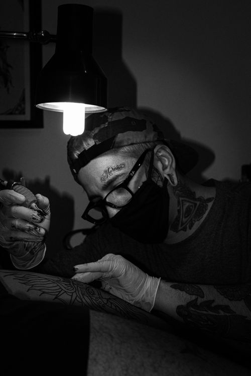 Tattoo artist working on a client's arm in the studio