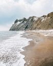 宁静的海滩上，海浪拍打着海岸，也拍打着积雪覆盖的岩石悬崖