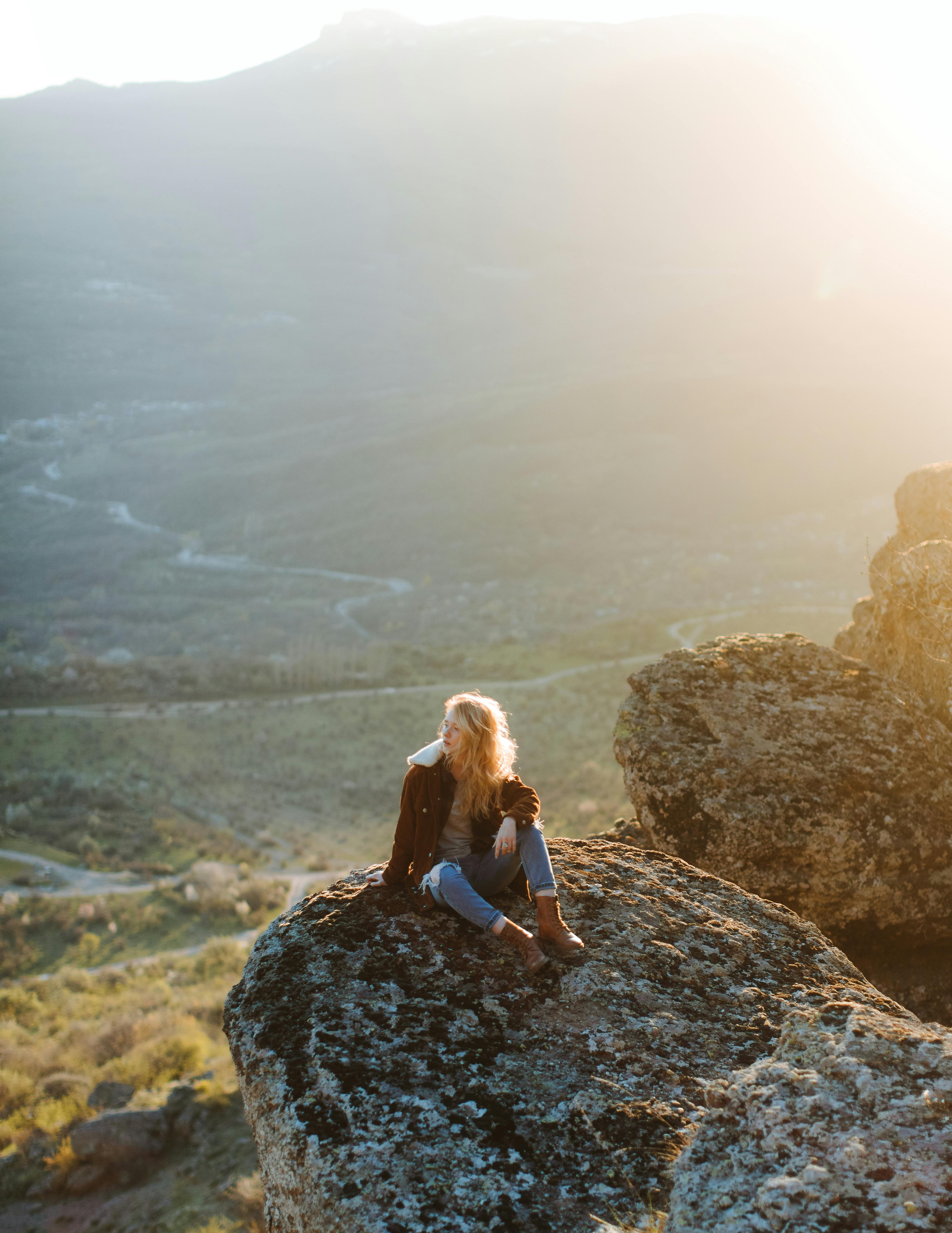 photo of woman sitting on rock