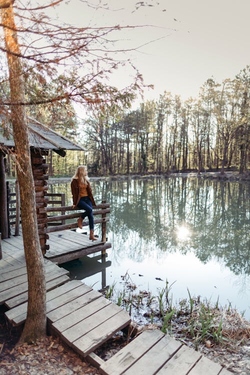 Photo of Woman Sitting on Wooden Dock Near Lake