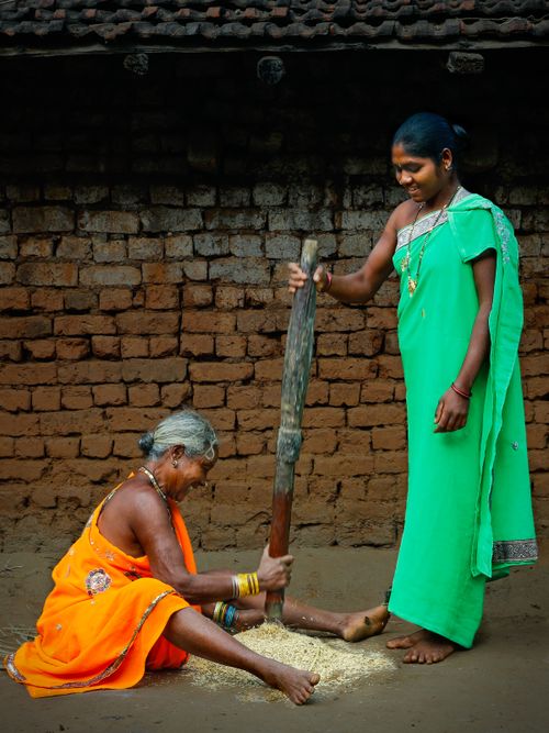 Free Two women in traditional attire process rice using cultural methods in Hanuman Junction, India. Stock Photo