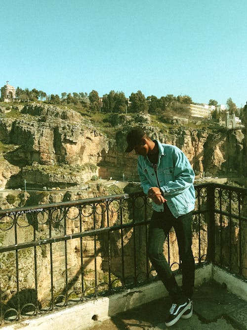 Young ethnic man standing on viewing platform and admiring view of rocky ravine