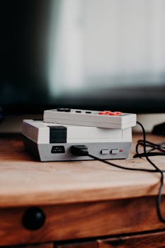 Vintage gaming console and controller on wooden desk, capturing nostalgic essence.