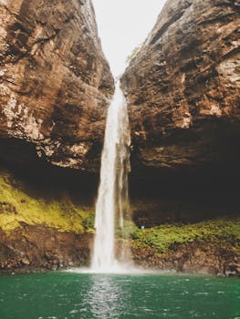 Stunning waterfall cascading down a rocky cliff surrounded by lush greenery in Patnus, India.
