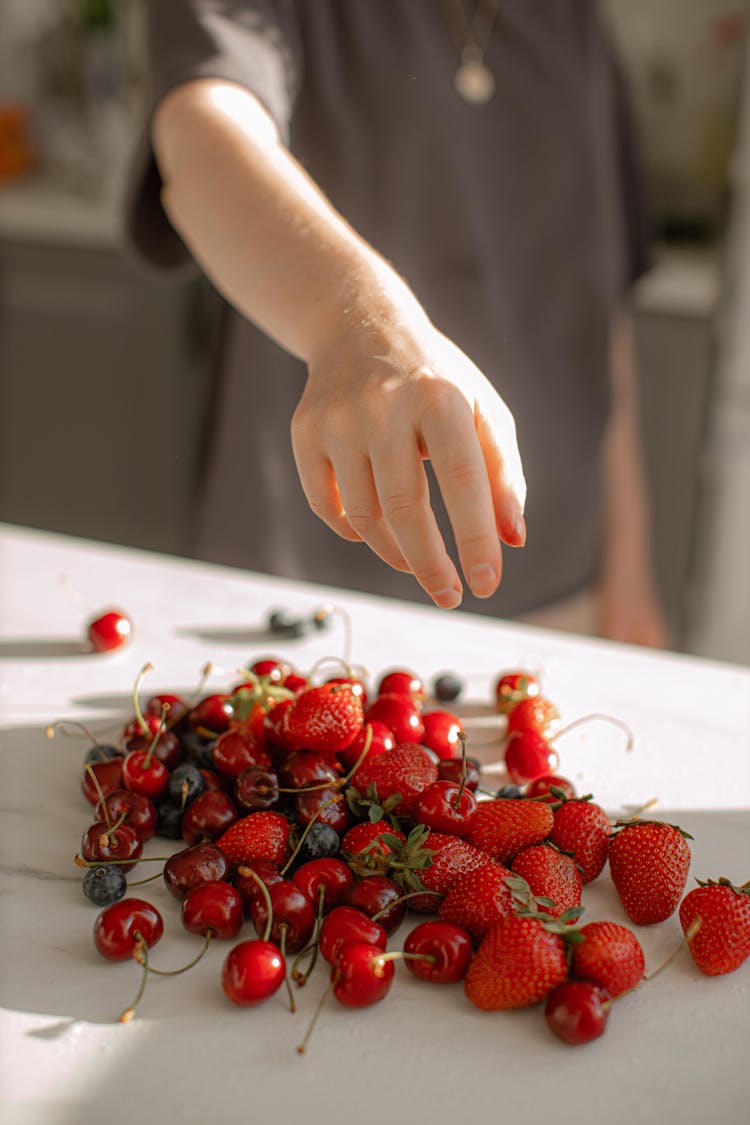 Photo Of Person's Hand Over Red Fruits