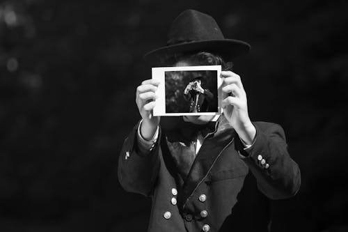 Grayscale Photo of a Person Holding Polaroid Picture