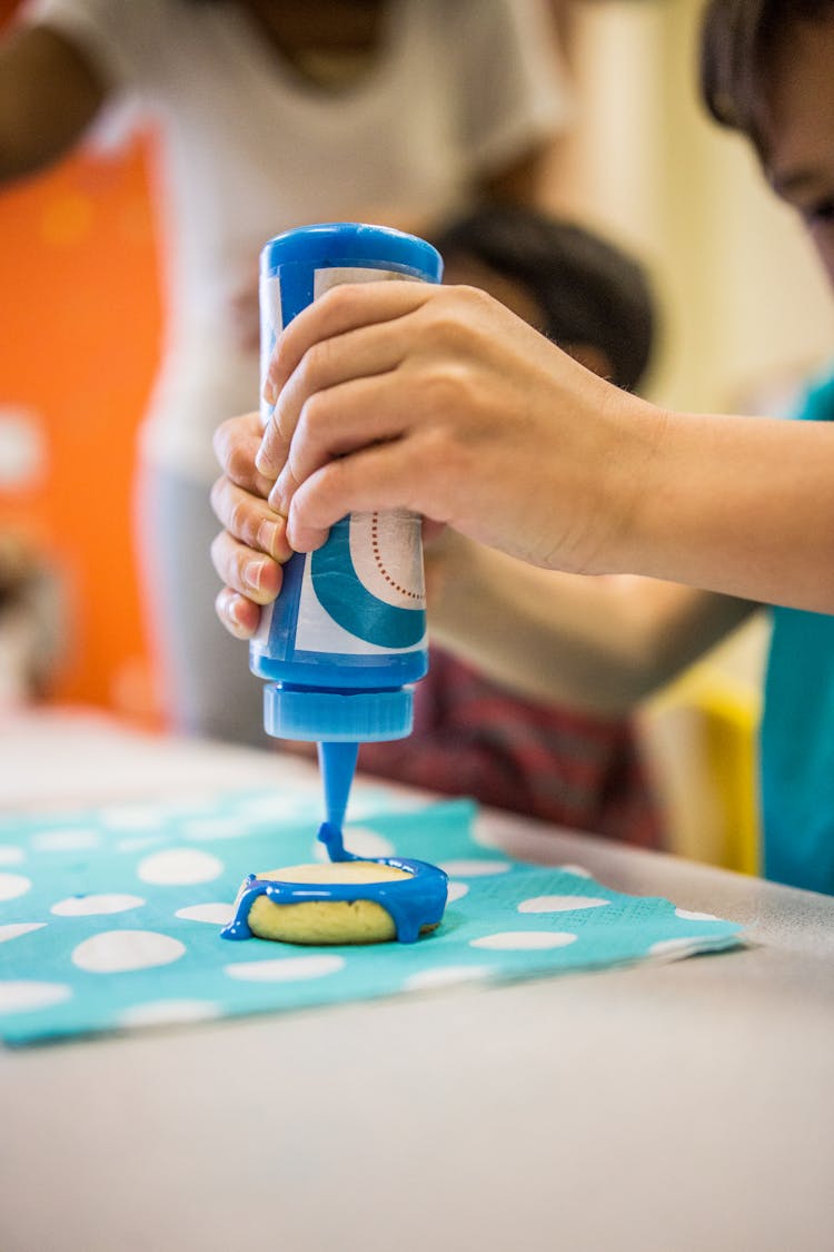 Crop Kid Decorating Biscuit With Glaze In Studio