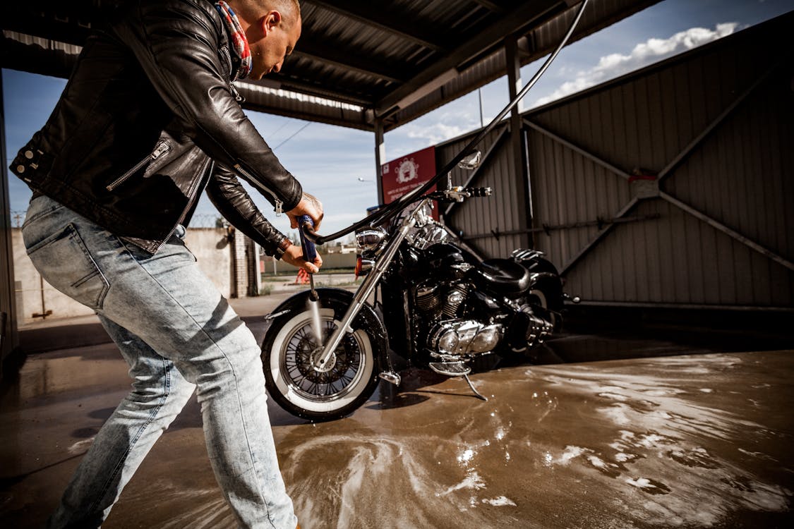 Photo of Man in Black Leather Jacket Cleaning His Motorcycle