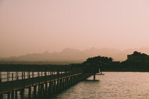 Free A serene view of a pier extending over water with mountains in the background at dusk in Egypt. Stock Photo