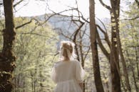 宁静的森林中，一位身穿白色连衣裙的孤独女子独自站立