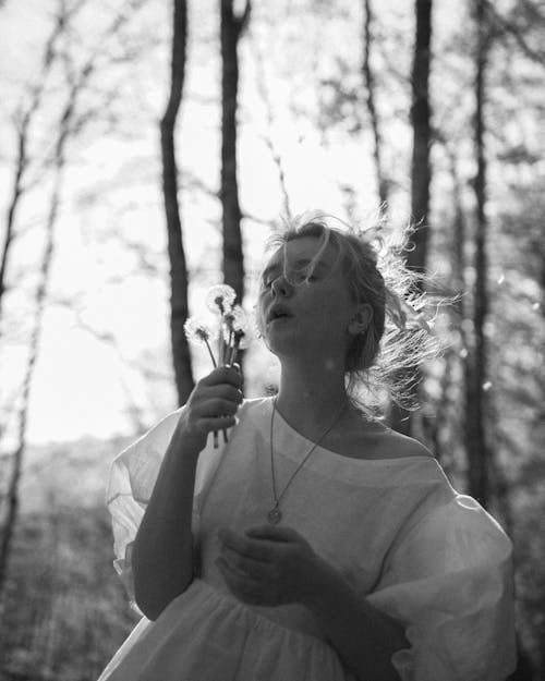 Grayscale Photo of Woman in Long Sleeve Shirt Holding Flower