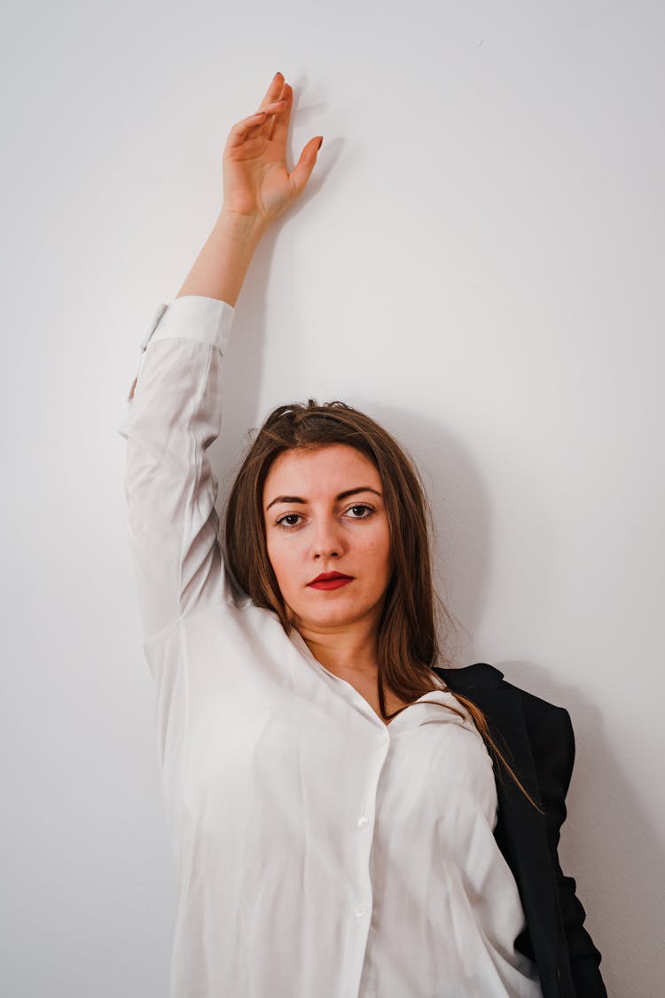 Confident Young Businesswoman Standing Near White Wall With Raised Hand