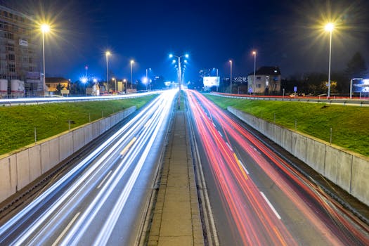 Long exposure night scene of a city highway with vibrant light trails from passing vehicles.