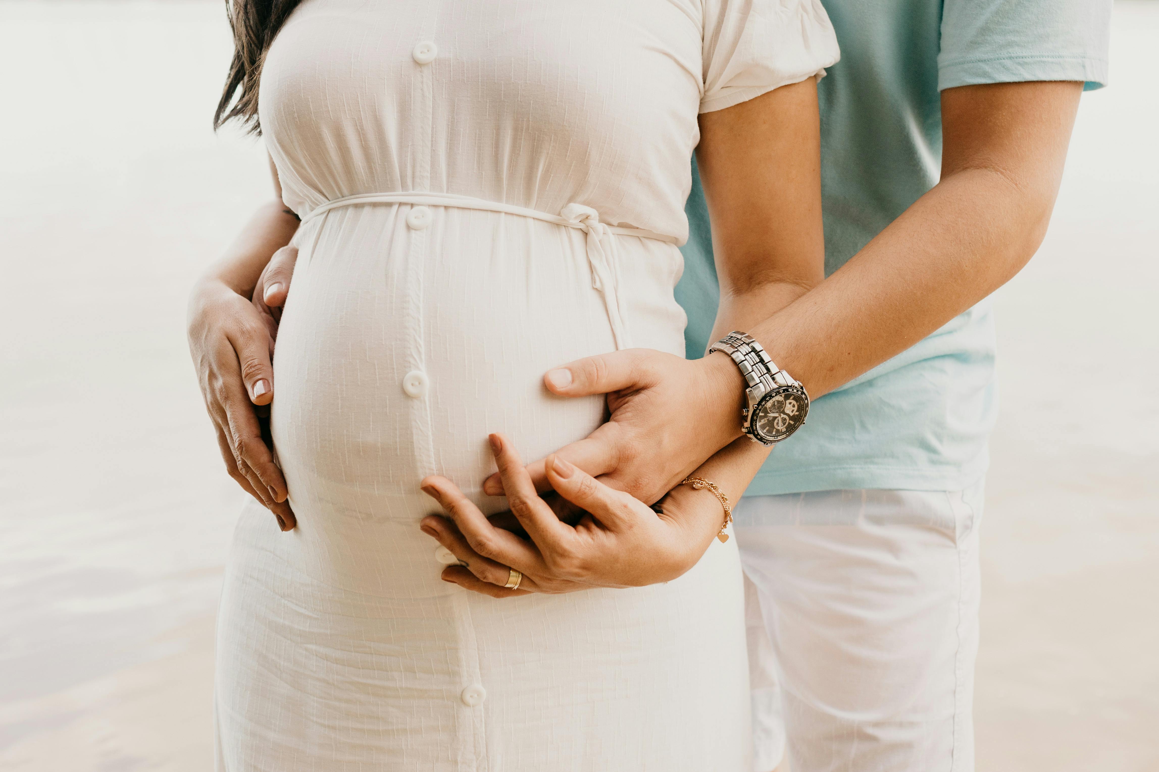 Pregnant woman embracing her tummy with her husband. | Photo: Pexels