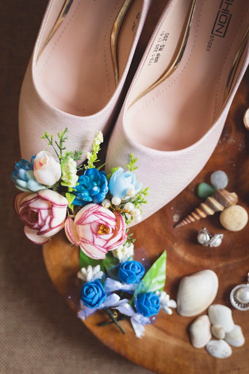 Pair of shoes on table with flowers and seashells