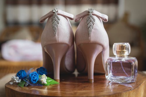Pair of bridal shoes and perfume on table with decorative flowers