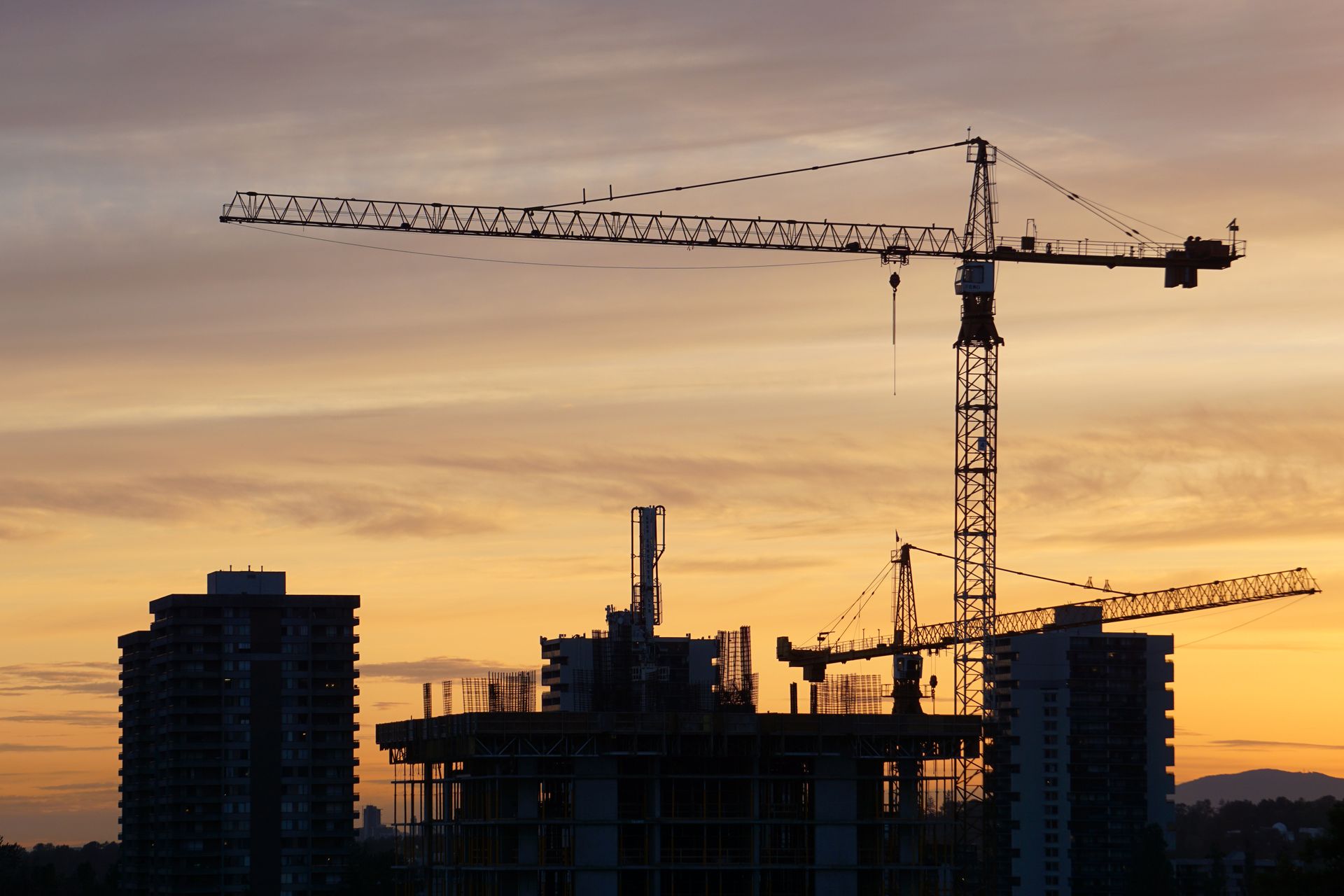 Tower crane silhouetted against the city skyline at dusk