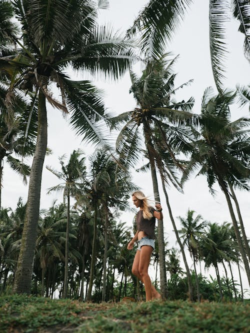 Photo of Woman Walking Near Palm Trees