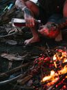 Crop unrecognizable man near bonfire with bottle of drink
