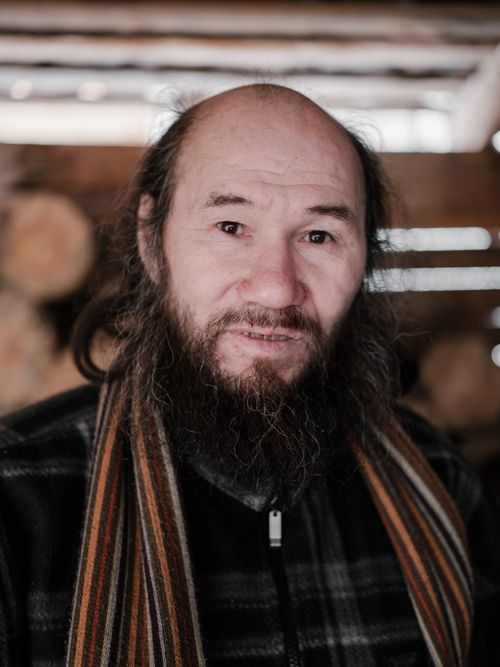 Free Portrait of pensive elderly bearded ethnic male in warm clothes looking at camera against wooden wall Stock Photo