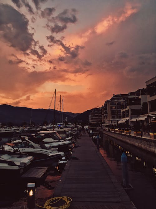 Picturesque scenery of beautiful sunset over harbor with moored yachts and ships and wooden pier