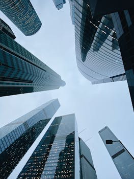 From below of modern skyscrapers with glass mirrored windows located in business district against blue cloudy sky