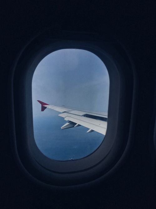 Free Through window of white wing of airplane flying on blue sky above clouds Stock Photo
