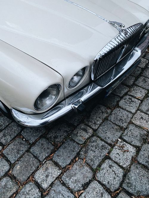 Free From above bonnet of shiny vintage car with round headlights and chrome details parked on cobblestone street in daytime Stock Photo
