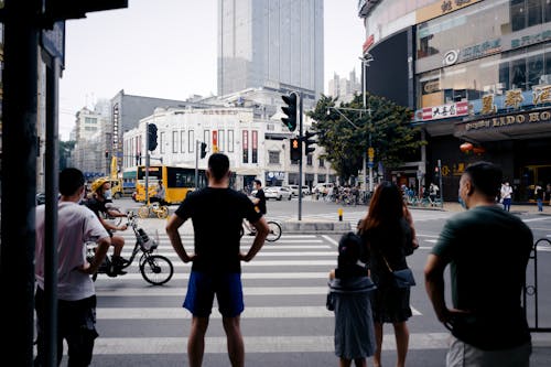 Back view of anonymous pedestrians standing on sidewalk near zebra crossing in modern city district