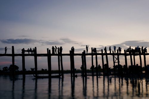Free Silhouettes of unrecognizable tourists walking on quay near rippling lake against picturesque purple sunset sky Stock Photo