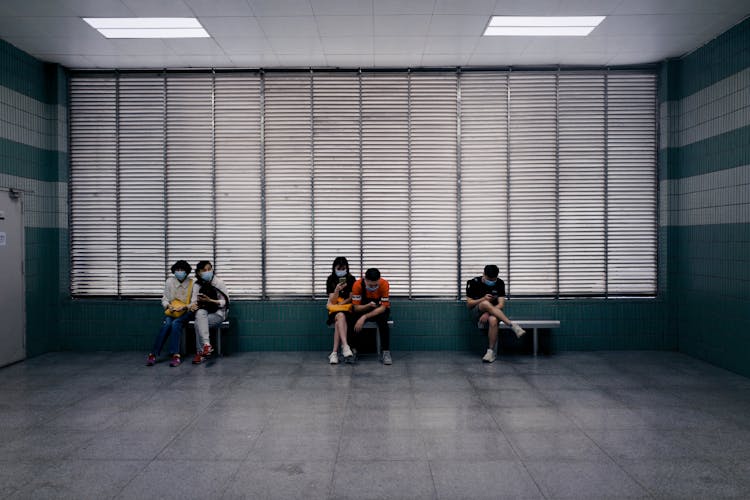 Anonymous People Waiting In Spacious Corridor Of Medical Center