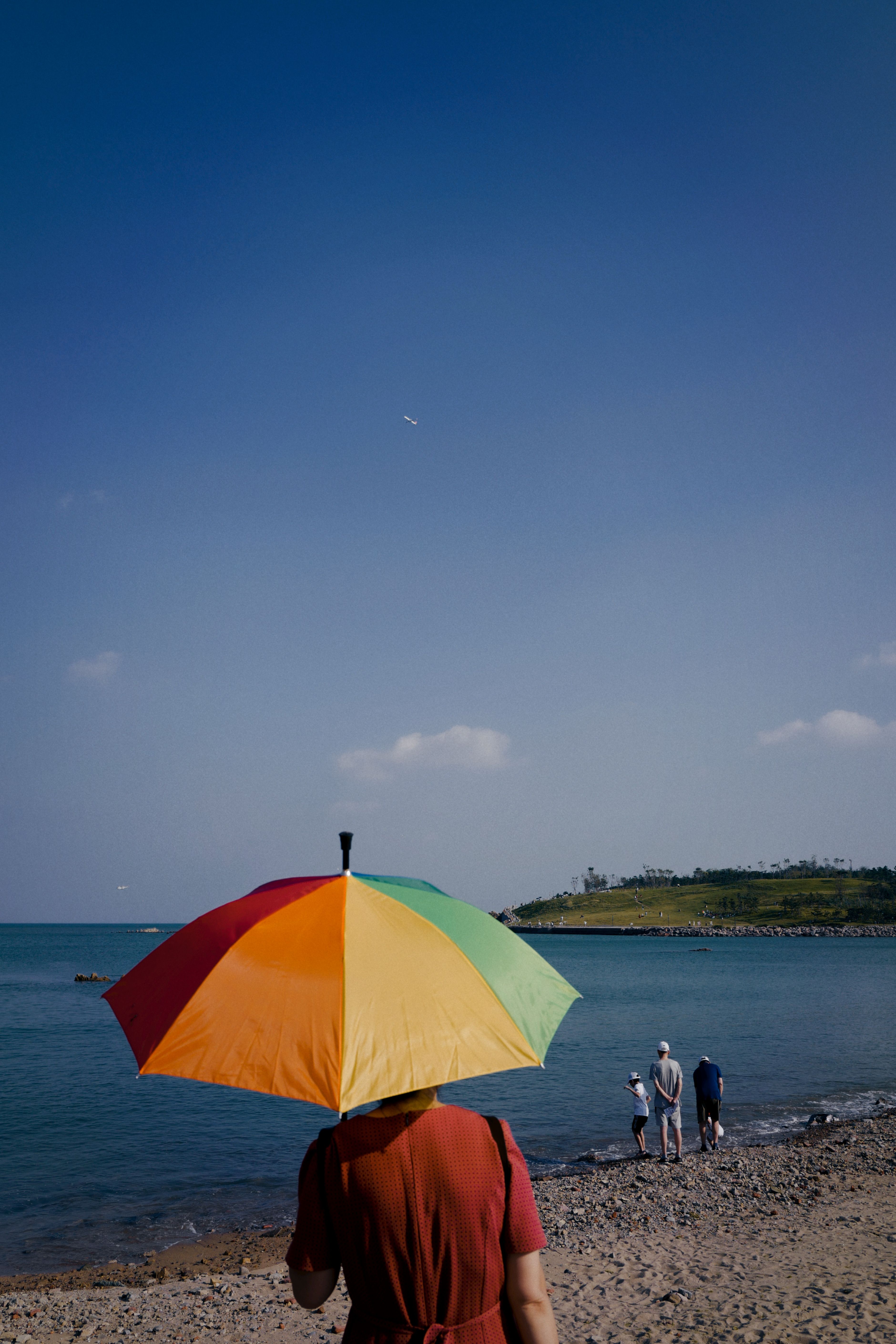 海滩上，一把充满活力的雨伞下，人们正享受着明媚的阳光