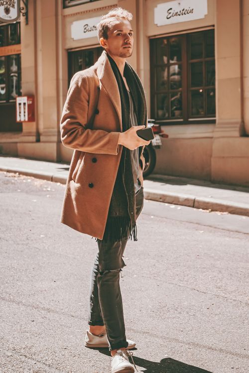 Free Stylish young male in trendy coat with smartphone in hand walking on street near modern buildings on sunny day Stock Photo