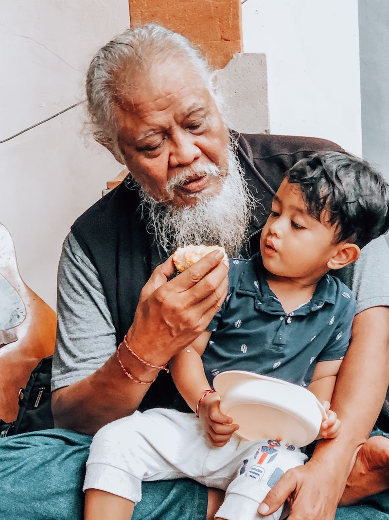 A senior grandfather hugging his young grandson at the lunch table