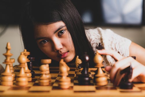 Woman in White Lace Shirt Playing Chess