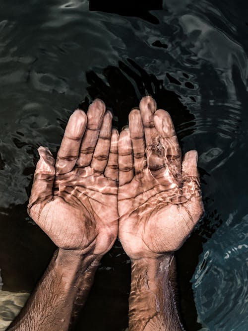 Free From above of crop anonymous male washing hands in clean water of lake in daytime Stock Photo