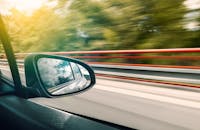 侧镜视图捕捉到高速公路上车辆飞驰的运动模糊效果