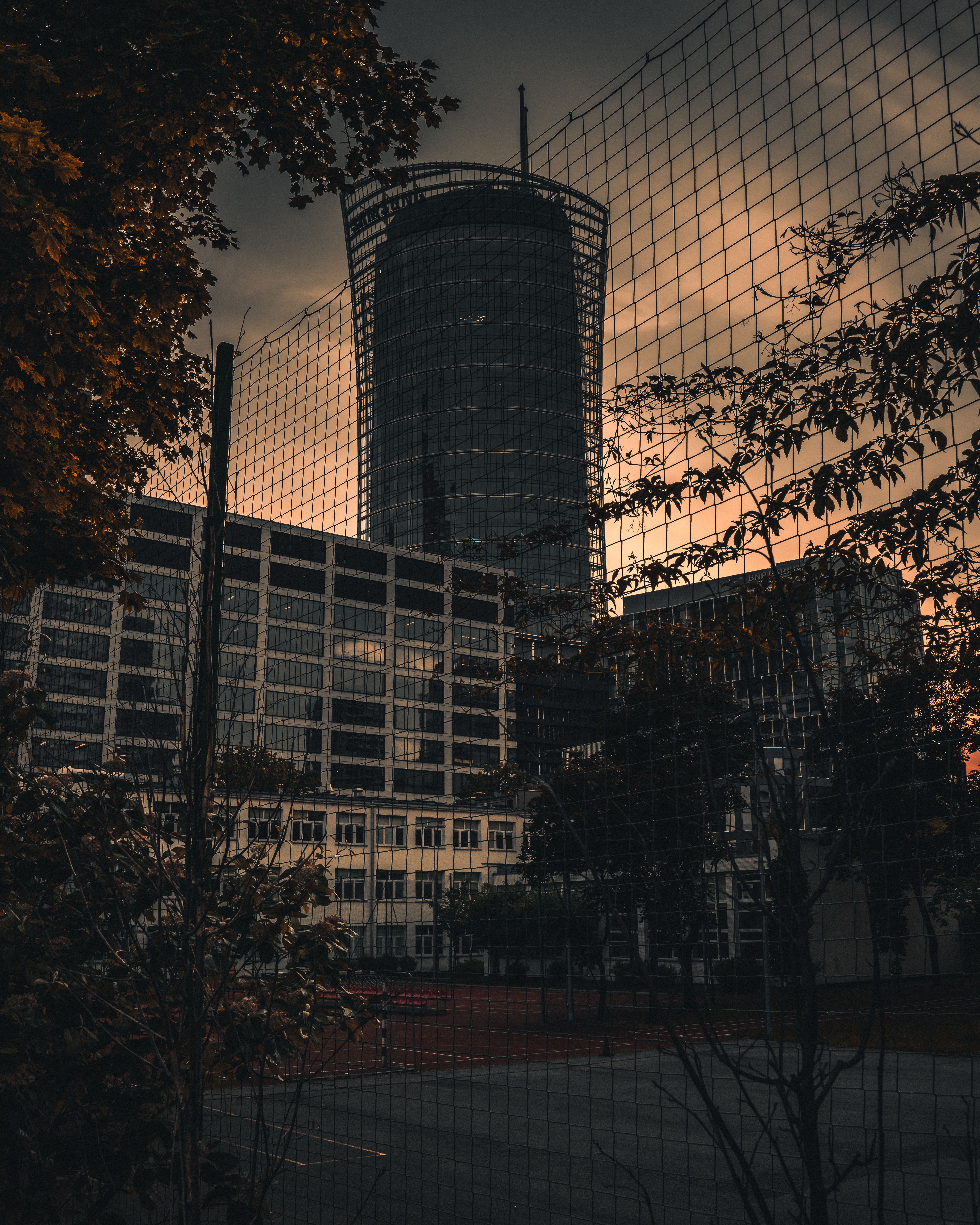 华沙日落时分，前景是带有铁丝网围栏的高层建筑