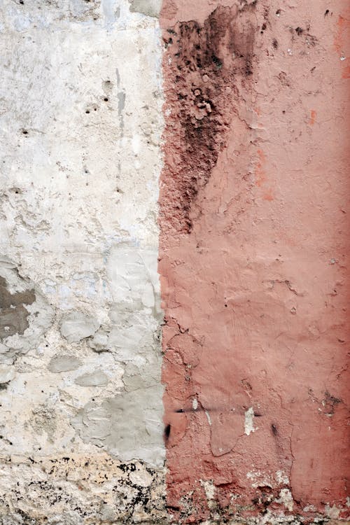 Closeup abstract background of white and pink aged shabby wall with cracks and rough texture